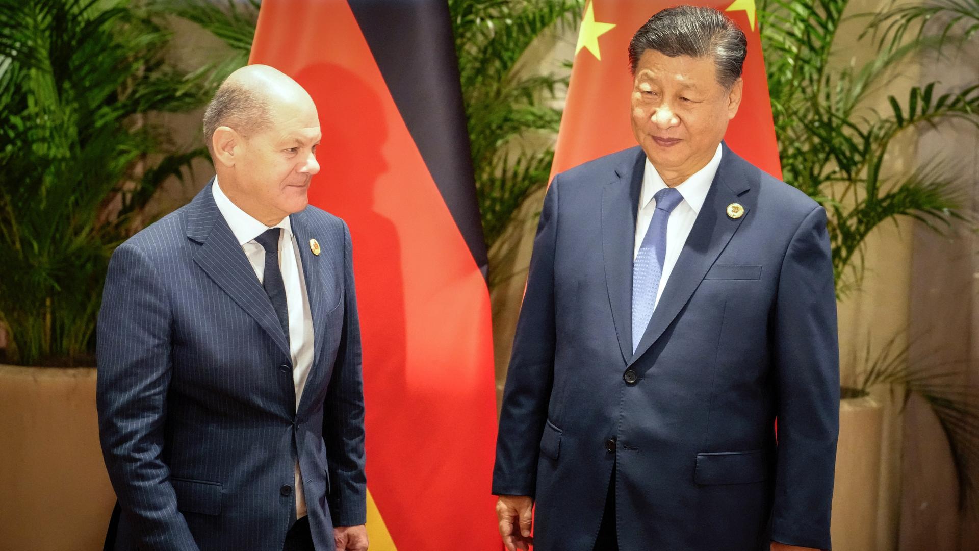 Rio De Janeiro: Bundeskanzler Olaf Scholz (l, SPD) und Xi Jinping, Staatspräsident der Volksrepublik China, stehen nebeneinander, hinter ihnen die Landesfahnen.