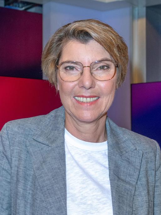 Bettina Böttinger mit wei2em T-Shirt und grauer Jacke im Studio bei Maischberger. Sie guckt in die Kamera.