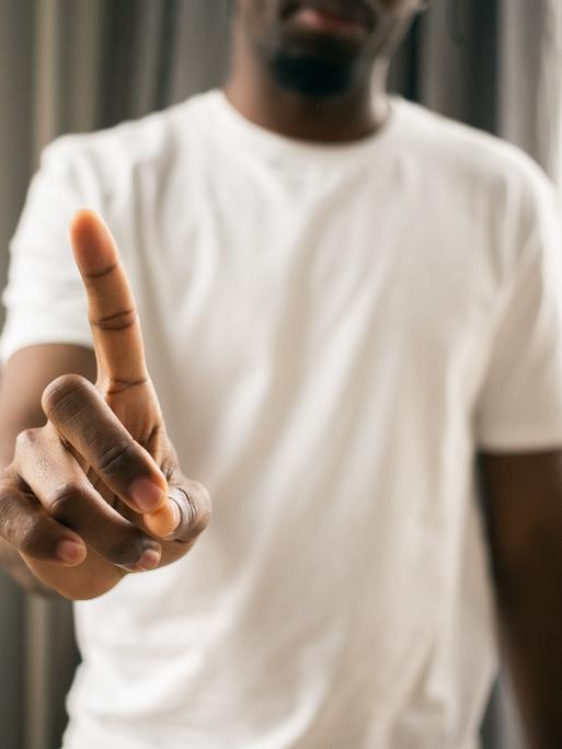 Ein Mensch macht eine Geste des Verneinenes mit den Fingern. Ein Mensch macht eine Geste des Verneinenes mit den Fingern.