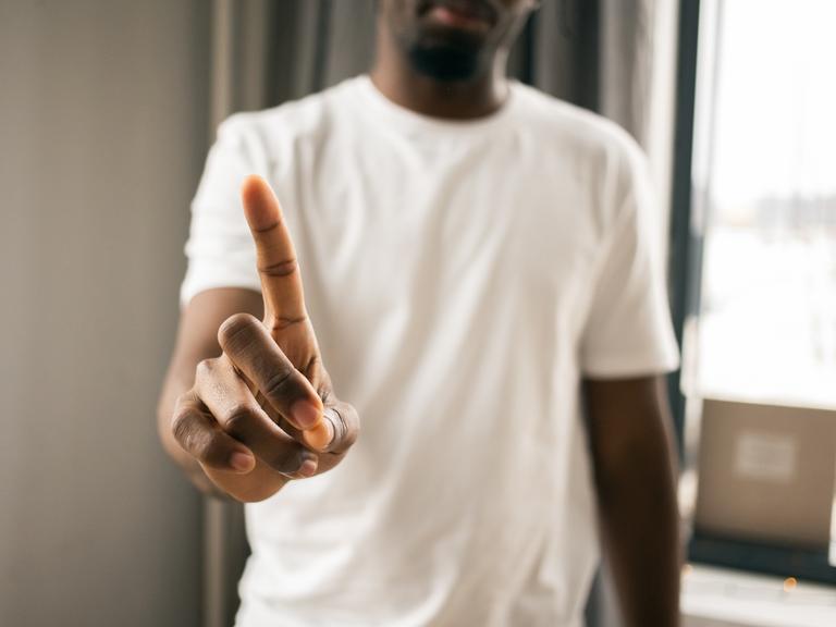 Ein Mensch macht eine Geste des Verneinenes mit den Fingern. Ein Mensch macht eine Geste des Verneinenes mit den Fingern.