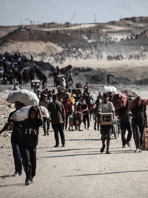 Palästinenser tragen am 5. Oktober 2025 Säcke und Kisten mit Nahrungsmittelhilfe durch den Gazastreifen in Netzarim, wo sich trotz der Gefahren Menschenmengen an einem Verteilungspunkt versammelten.