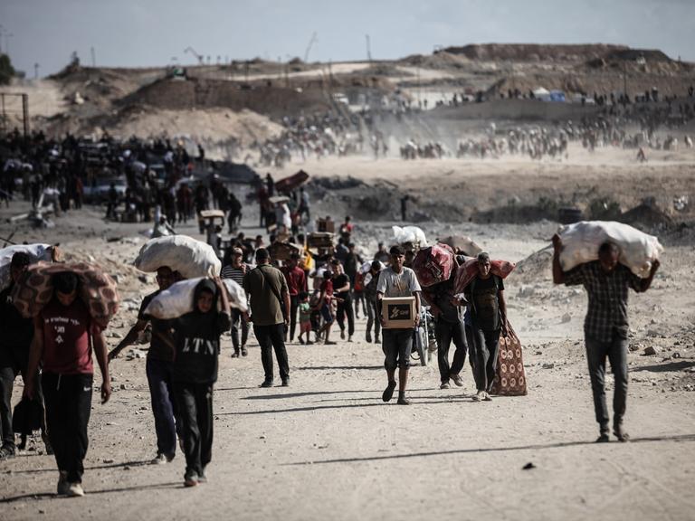 Palästinenser tragen am 5. Oktober 2025 Säcke und Kisten mit Nahrungsmittelhilfe durch den Gazastreifen in Netzarim, wo sich trotz der Gefahren Menschenmengen an einem Verteilungspunkt versammelten.
