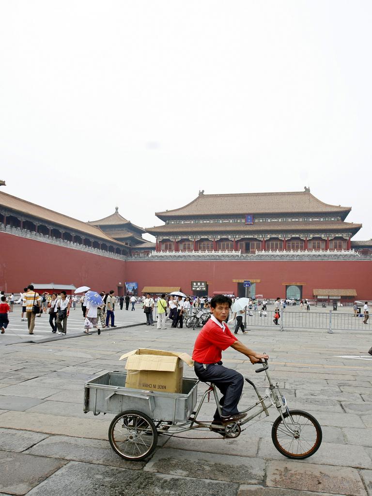 Ein Mann fährt mit einem Lastenfahrrad durch die Verbotene Stadt, während dort auch viele Touristen unterwegs sind.