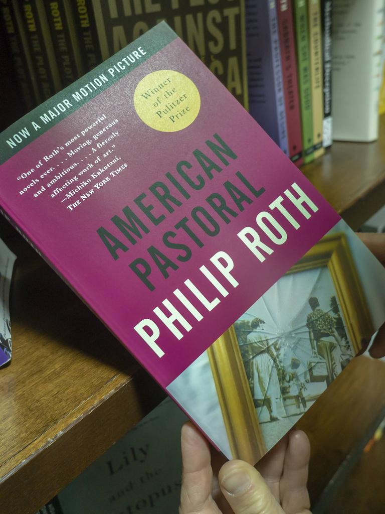 Ein Mann hält den Roman "Amerikanisches Idyll" (engl. "American Pastoral") von Philip Roth in den Händen.