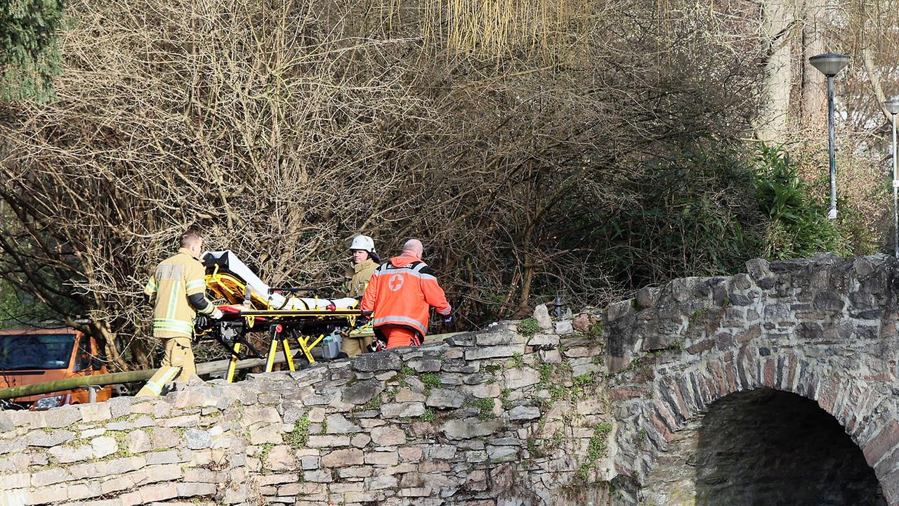 Rettungs-Kräfte gehen in der Nähe eines Tat-Ortes in Aschaffenburg eine kleine Brücke hinauf. 