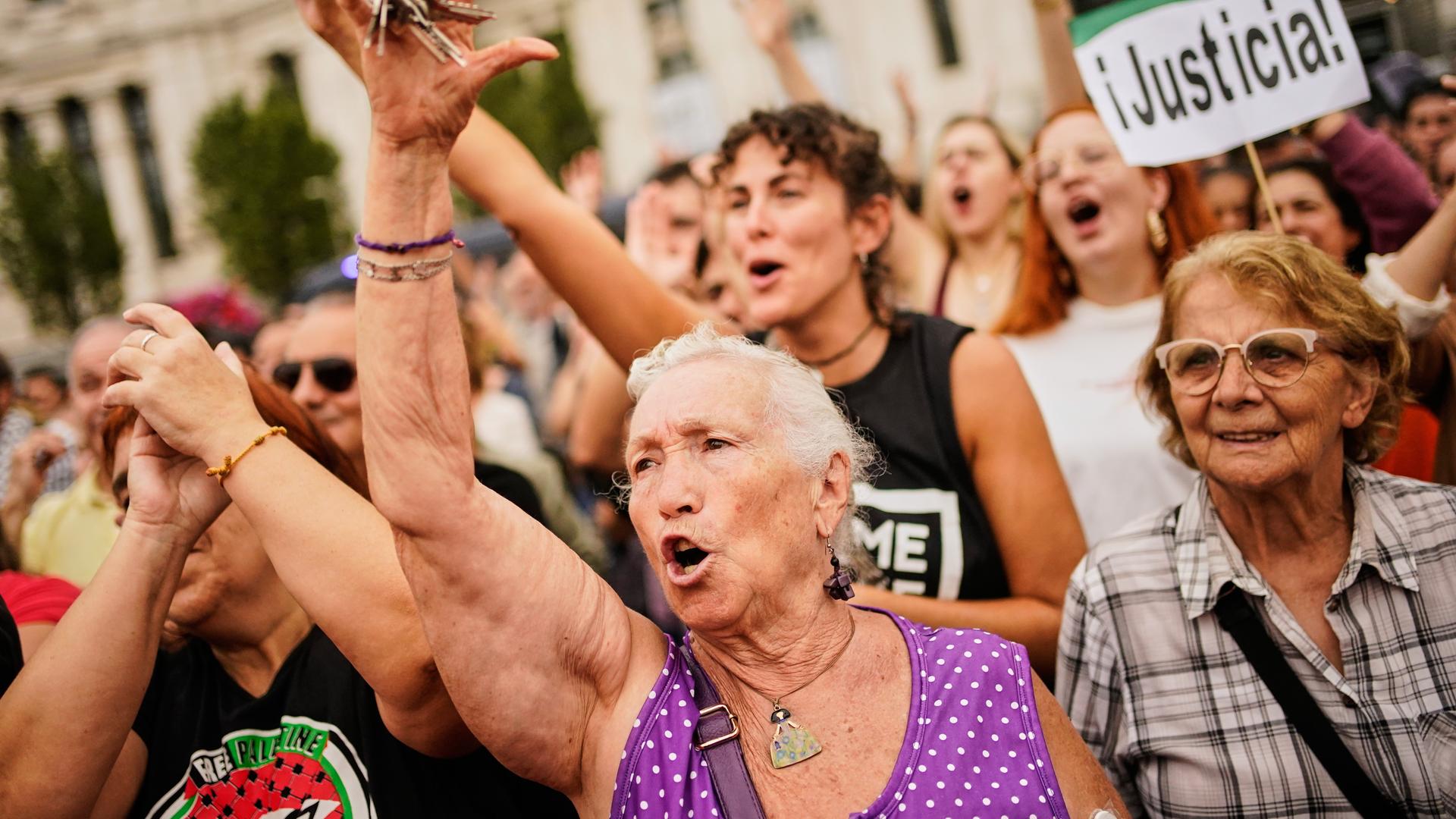 Menschen stehen dicht gedrängt bei einer Demonstration. Einige halten Schilder hoch. 
