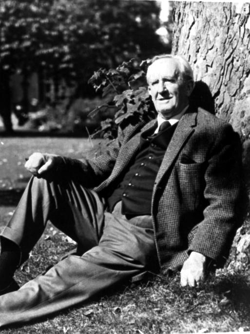 J.R.R. Tolkien sitzt auf einer Wiese und lehnt dabei an einem Baum
