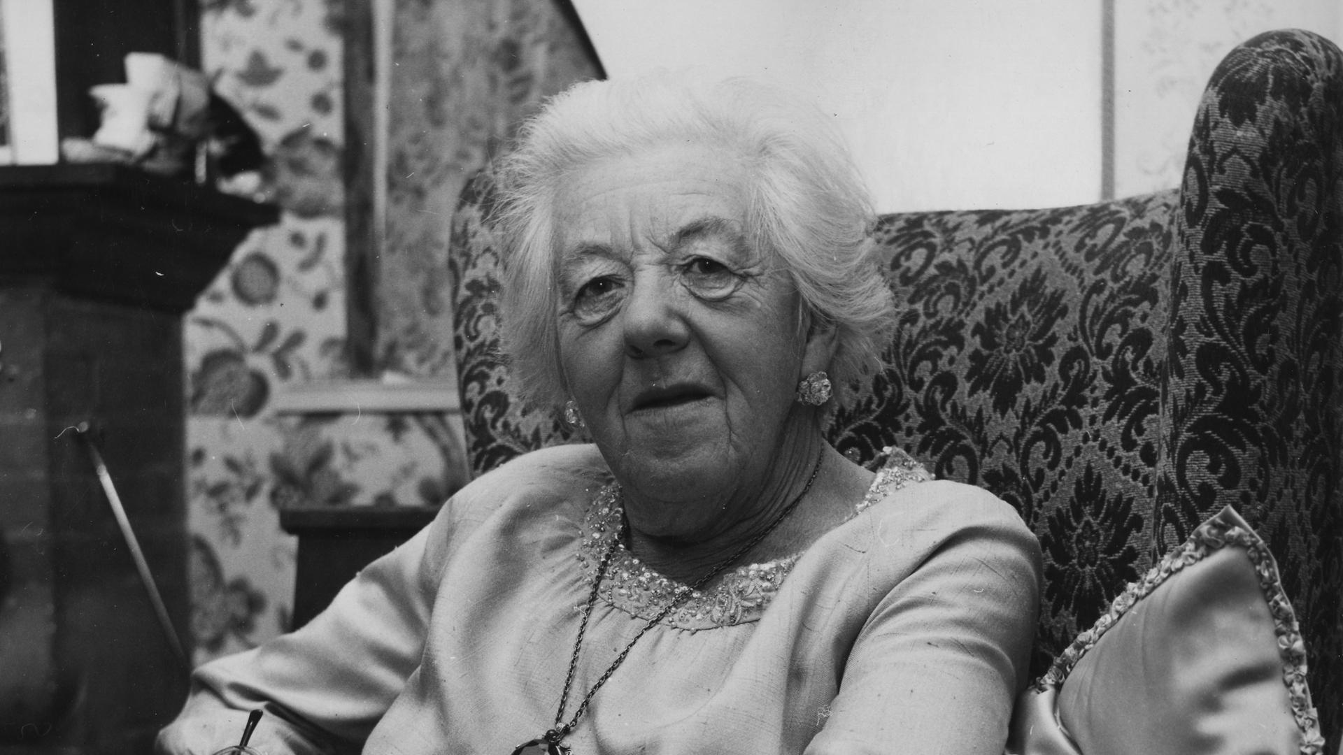 Die britische Schauspielerin Margaret Rutherford sitzt in einem Sessel.