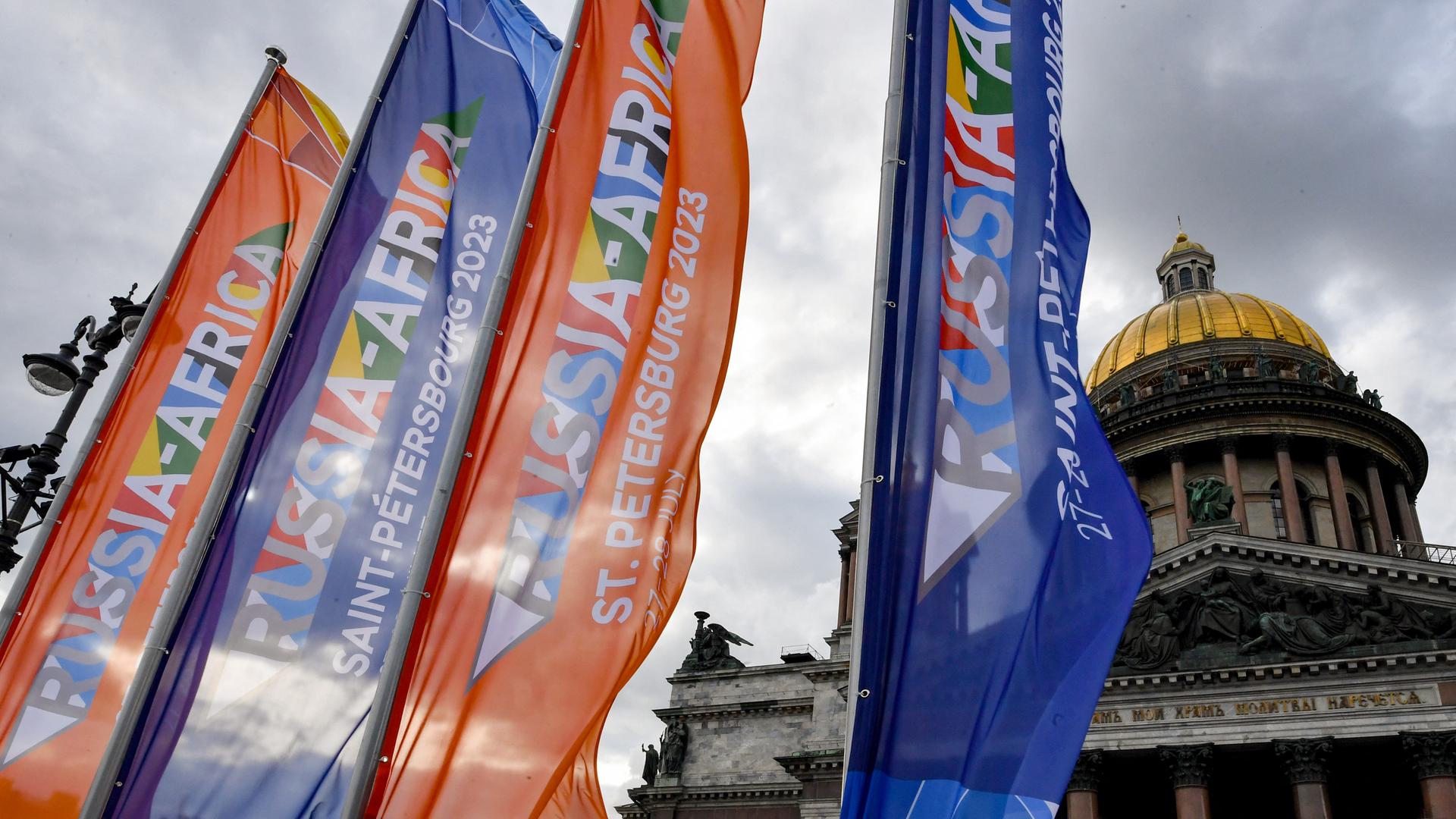 Flaggen mit dem Logo des Gipfeltreffens wehen in verschiedenen Farben vor der Isaakskathedrale in Sankt Petersburg.