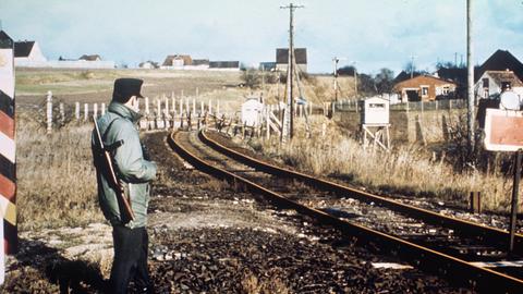 Blick auf den Bahnübergang bei Dankmarshausen am 01.12.1967, der von den Behörden der DDR gesperrt wurde. Das Bild zeigt einen Beamten des Bundesgrenzschutzes vor dem Stoppschild und im Hintergrund die Sperrung der DDR.