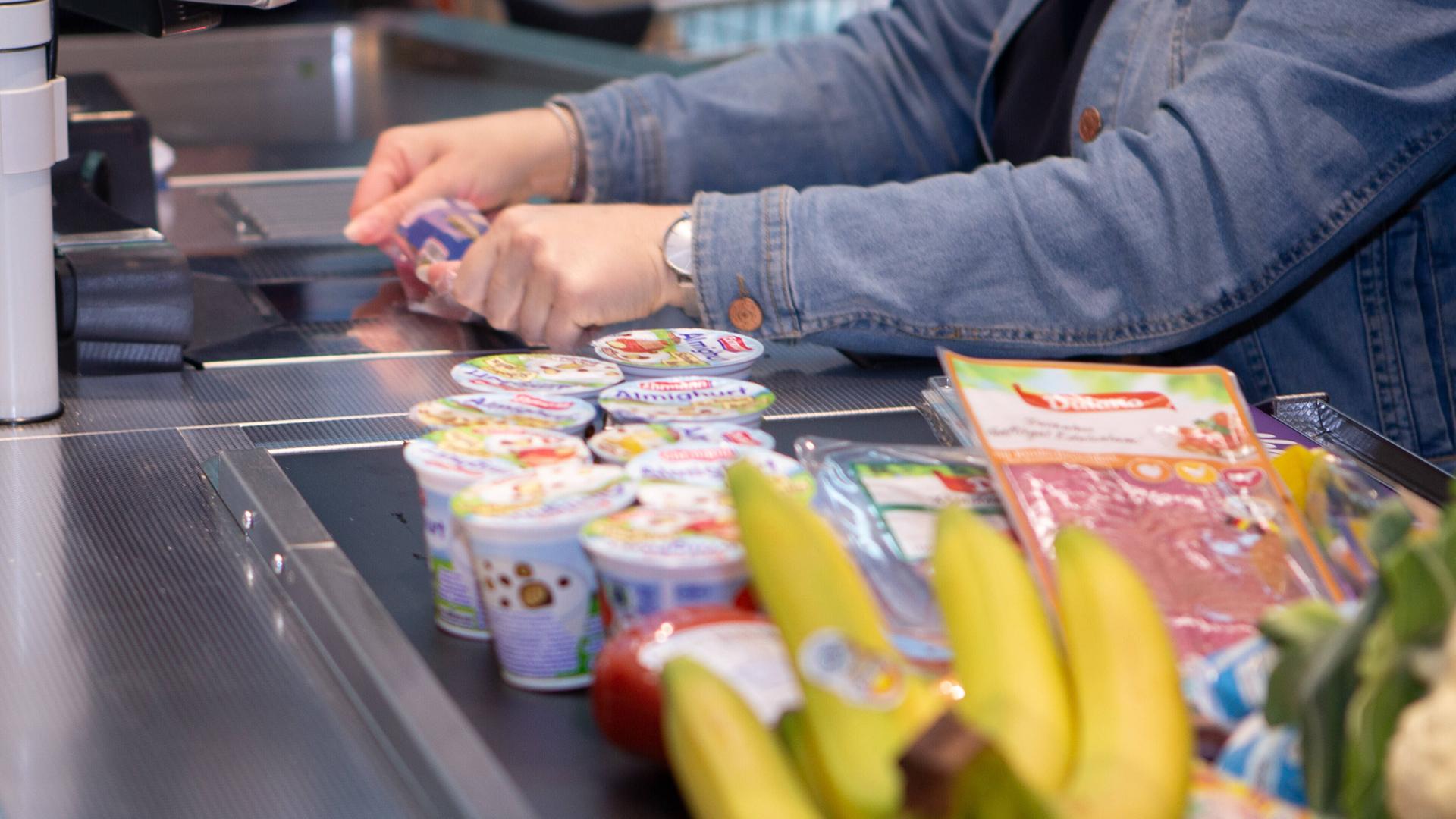 Eine Mitarbeiterin in einem Lebensmittel-Discounter zieht einen Artikel über den Scanner der Kasse. Eine Mitarbeiterin in einem Lebensmittel-Discounter zieht einen Artikel über den Scanner der Kasse.