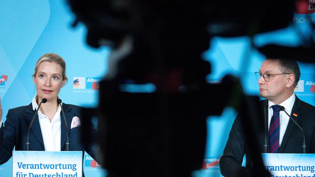 Die AfD-Bundesvorsitzenden Alice Weidel und Tino Chrupalla stehen bei einer Pressekonferenz hinter Pulten, dazwischen ist die Silhouette einer Kamera zu sehen