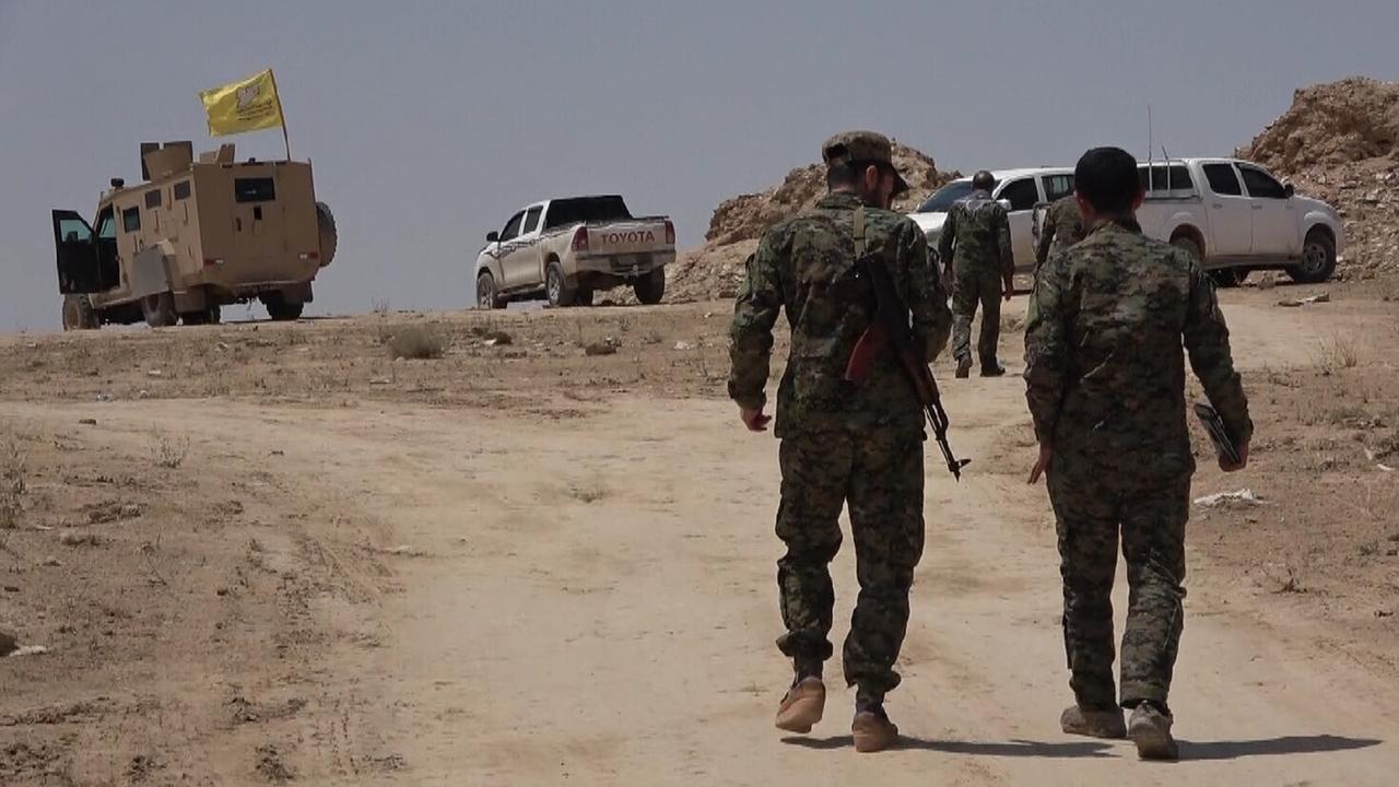 Bewaffnete Männer auf einer staubigen Straße in der nordsyrischen Region Manbij