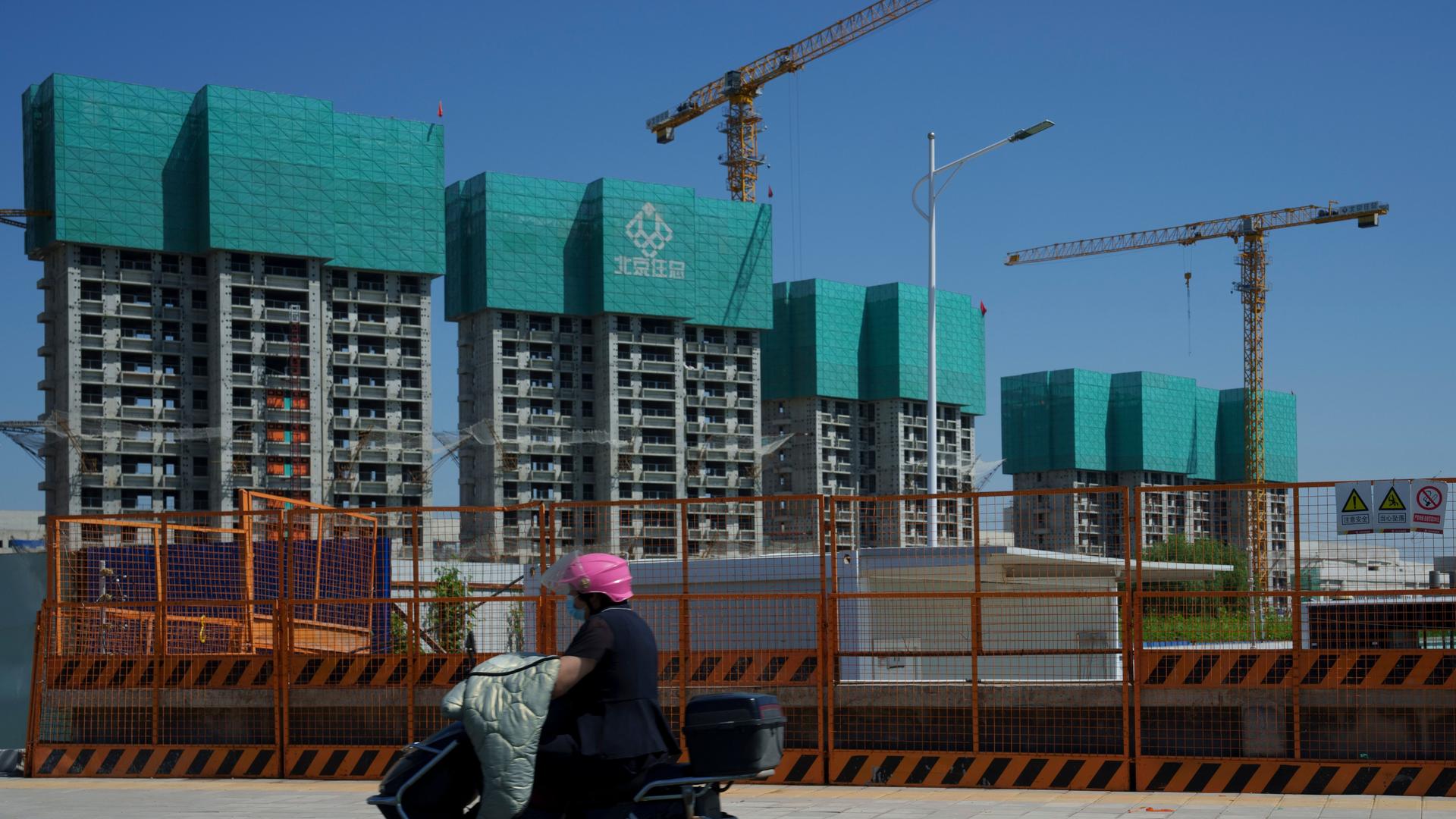Peking: Eine Frau fährt an einem im Bau befindlichen Wohnprojekt am Stadtrand von Peking vorbei. 