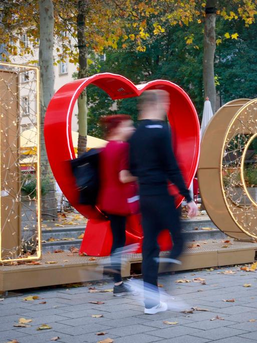 Zwei Menschen laufen durch die Innenstadtz von Chemnitz, hinter ihnen sieht man den erleuchteten Schriftzug "I love Chemnitz"