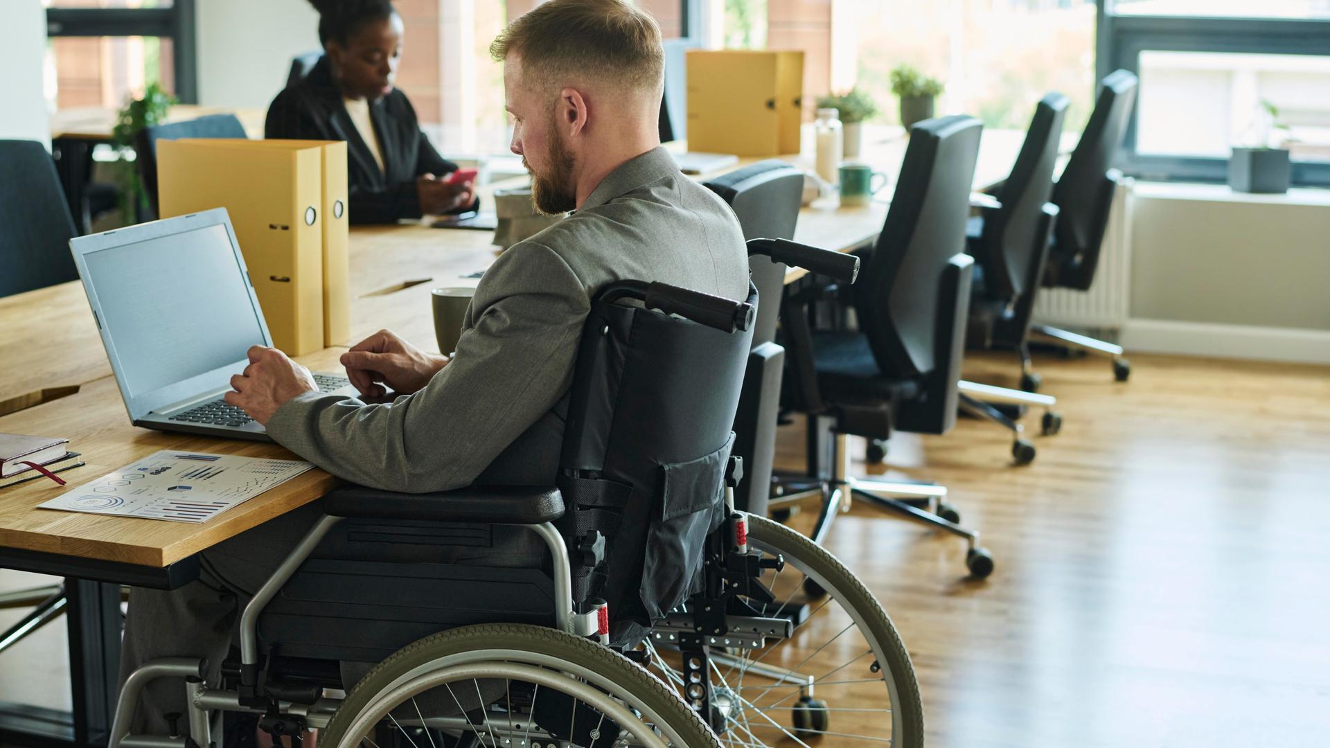 Ein Mann mit Rollstuhl arbeitet in einem Büro.