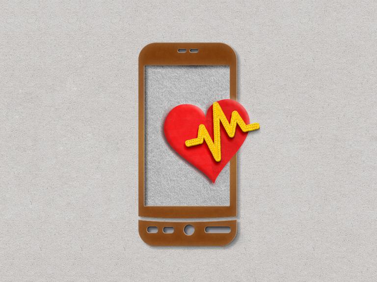 Papierschnitt eines Mobiltelefons mit rotem Herz und und EKG-Kurve. 