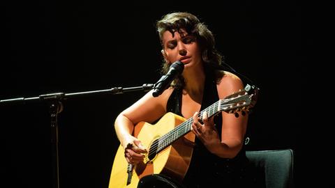 Die georgisch-britische Singersongwriterin Katie Melua gibt am 3.9.2021 ein Konzert. Die dunkelhaarige Frau trägt ein dunkles, ärmelloses Oberteil, spielt auf ihrer Gitarre und singt.