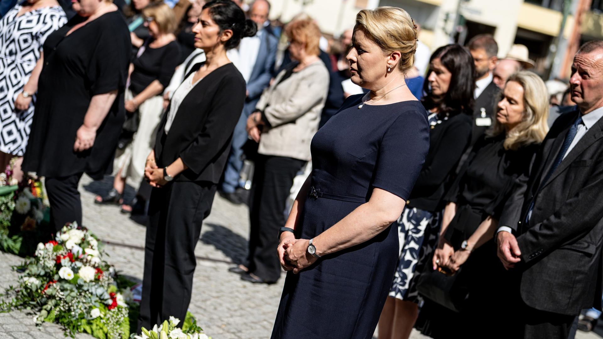 Franziska Giffey (SPD) im dunkelblauen Kleid nimmt an der Kranzniederlegung zum Gedenken des 62. Jahrestag des Baus der Berliner Mauer teil.