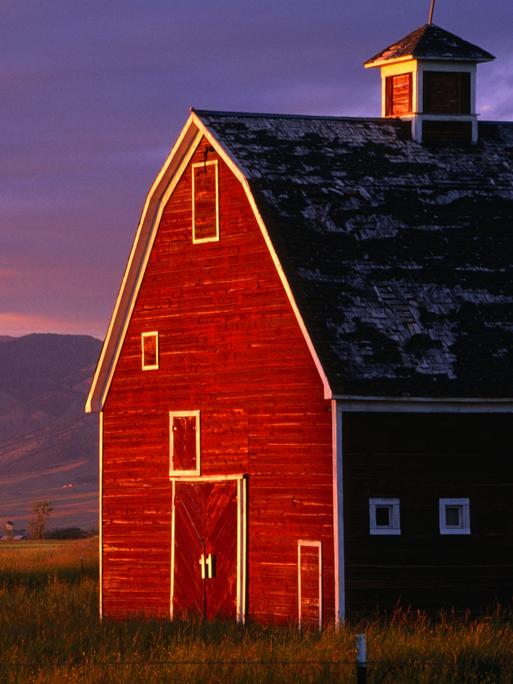 Ein rotes Farmhouse in Montana, USA, im Sonnenuntergang.