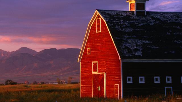 Ein rotes Farmhouse in Montana, USA, im Sonnenuntergang.