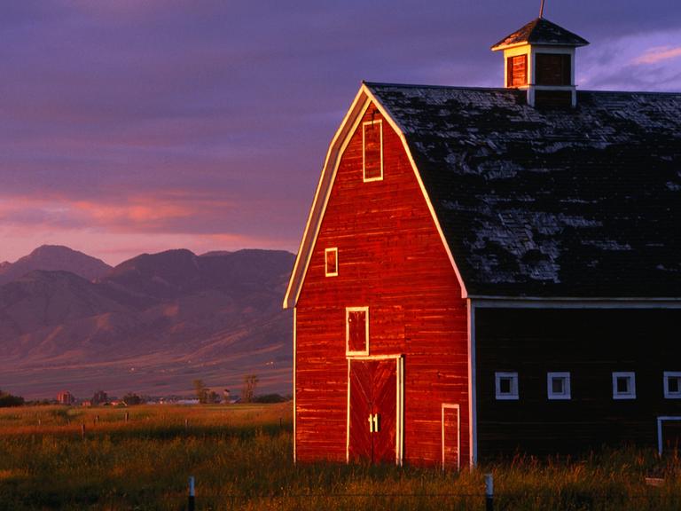 Ein rotes Farmhouse in Montana, USA, im Sonnenuntergang.