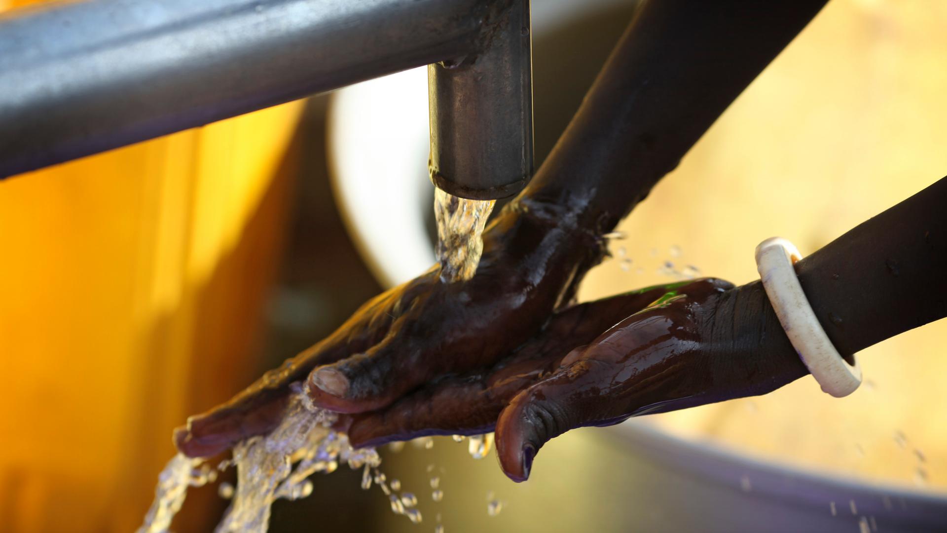 Hände mit Wasser aus einem Brunnen in Südsudan. 