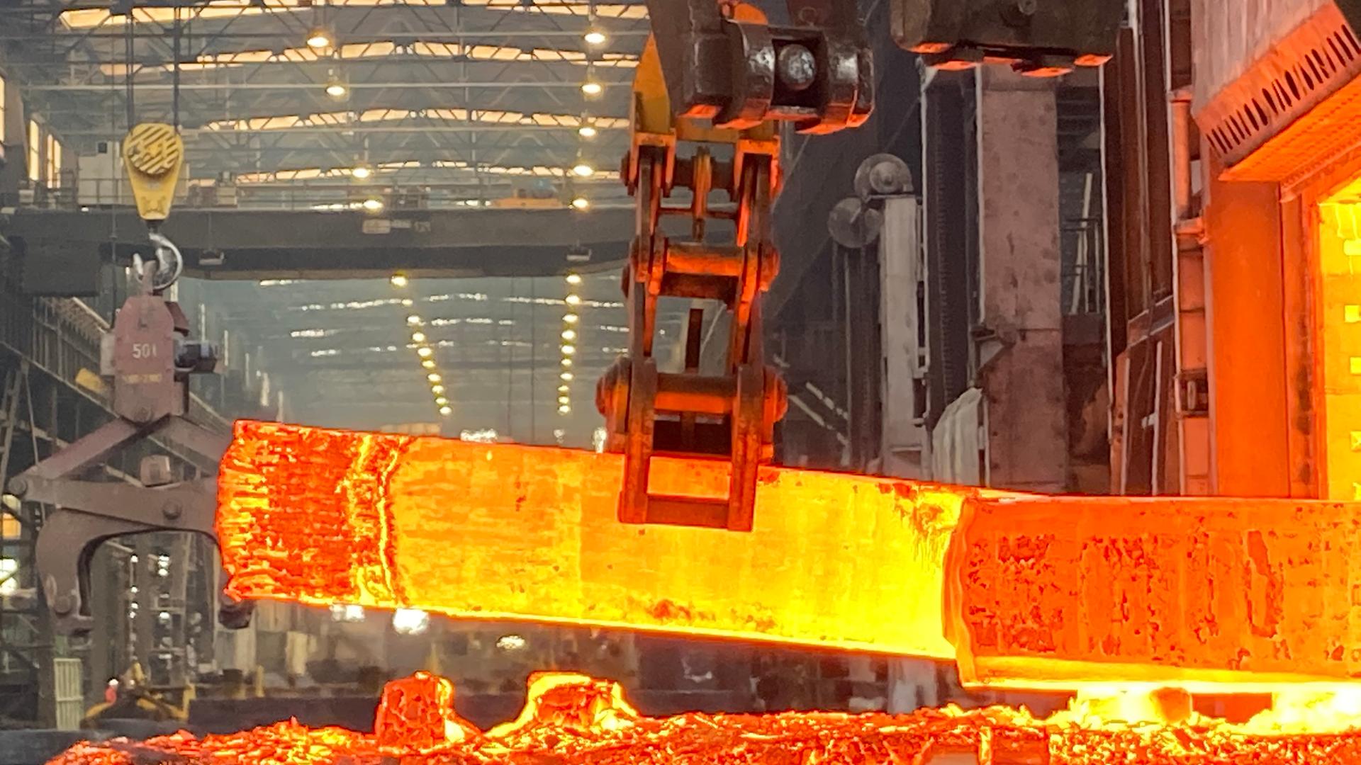 Ein glühendes Stück Stahl wird im Stahl- und Schmiedewerk Gröditz in Sachsen von einem Greifarm bewegt.