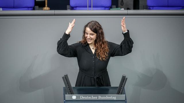 Das Foto zeigt die gehörlose Bundestags-Abgeordnete Heike Heubach. Sie hat beide Arme hochgehoben. 