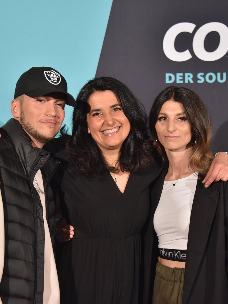 Cosmo-Redakteurin Schiwa Schlei (Mitte) mit Autor Patrick Phul (links) und Regisseurin Esra Phul. Sie stehen auf vor einer Fotowand zur Premiere der Rap-Musical-Serie "Hype", im Hintergrund rechts ist das Cosmo-Logo zu sehen. 
