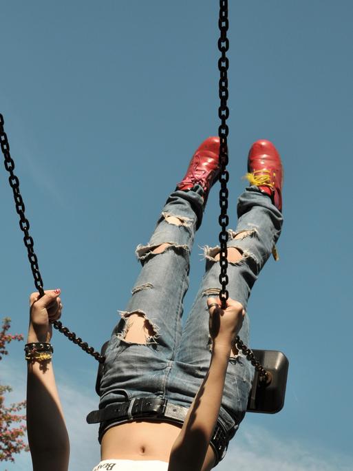 Eine Person mit Jeans schaukelt. 