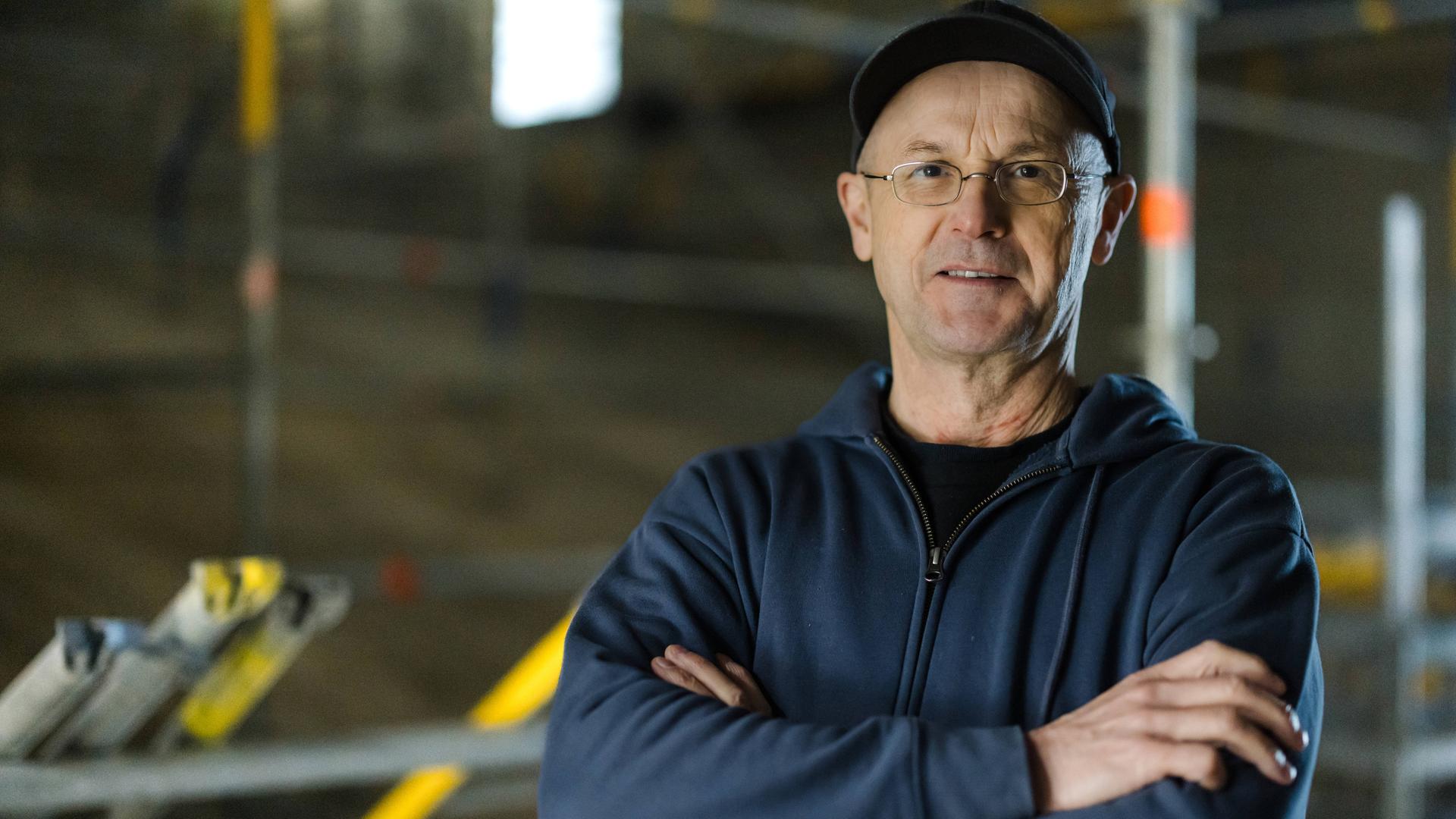 Steffen Mensching steht mit verschränkten Armen auf einer Baustelle seines Theaters in Rudolstadt.