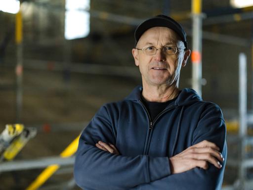Steffen Mensching steht mit verschränkten Armen auf einer Baustelle seines Theaters in Rudolstadt.