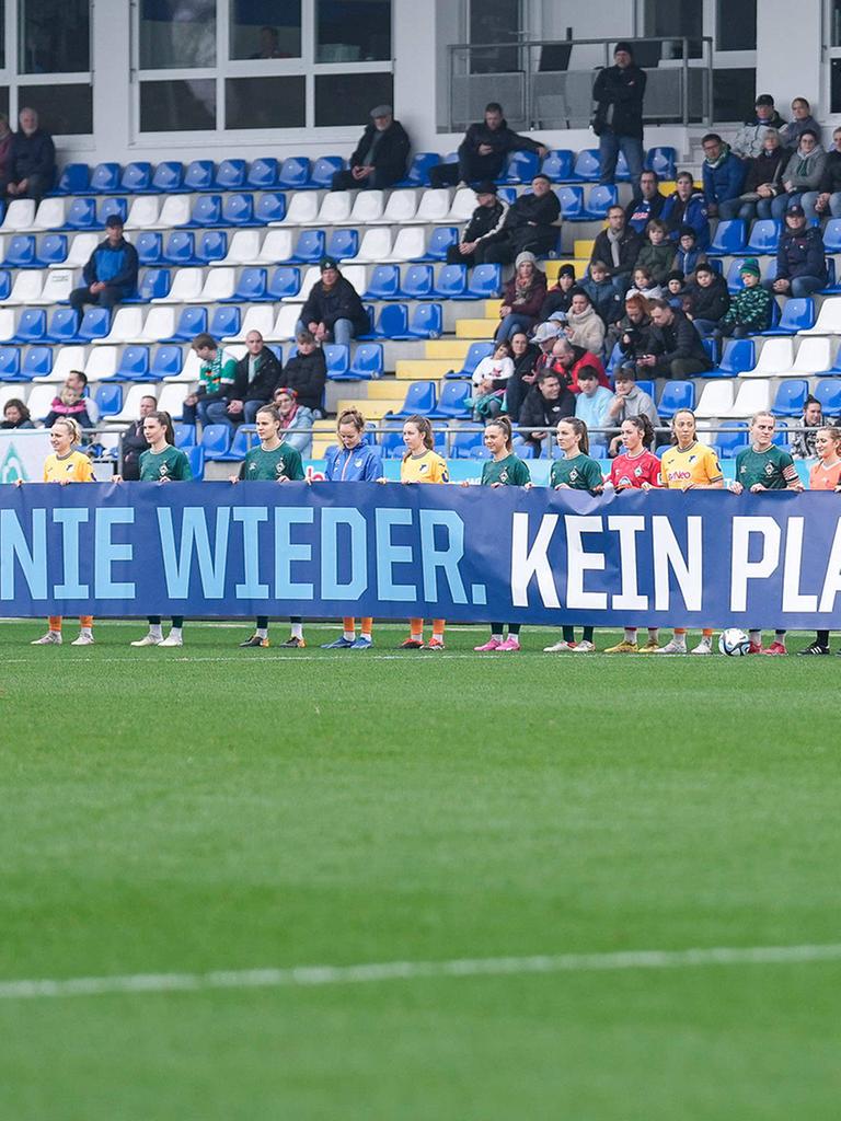 Spielerinnen von 1899 Hoffenheim und Werder Bremen mit einem Banner mit der Aufschrift "Nie wieder. Kein Platz für Antisemitismus" 