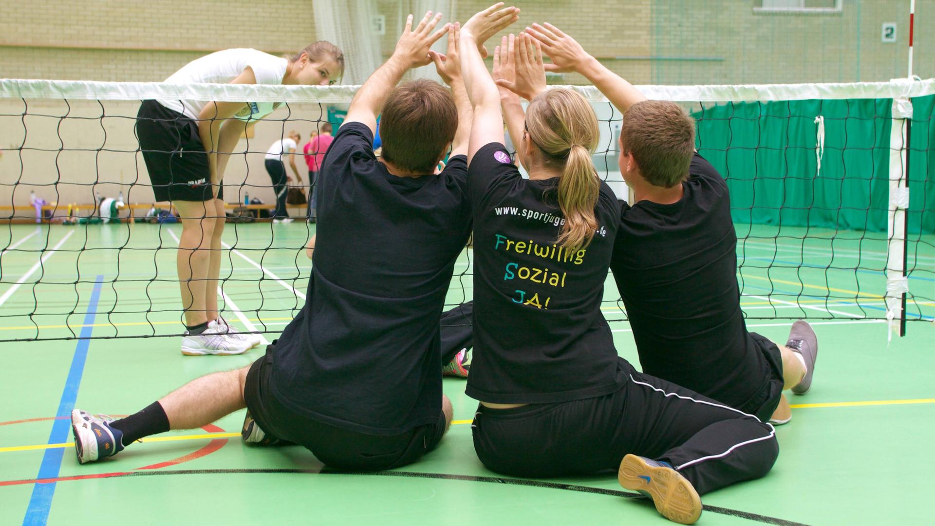 Jugendliche spielen Sitzvolleyball mit Menschen mit Behinderung. Seit 20 Jahren können Jugendliche auch in Sportvereinen ein freiwilliges soziales Jahr machen.