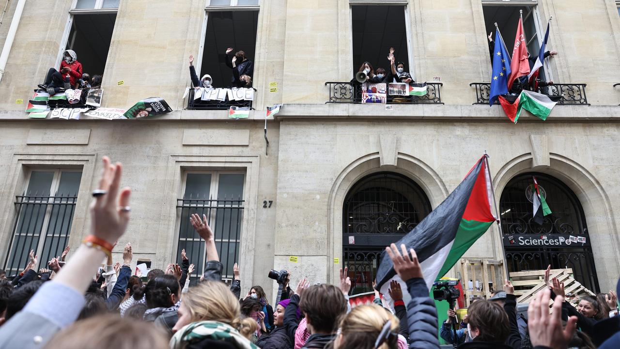 Blockade eines Universitätsgebäudes der Sciences Po Paris durch einen propalästinensichen Protest. Viele Menschen versperren den Haupteingang. Einige tragen Palästina-Flaggen.