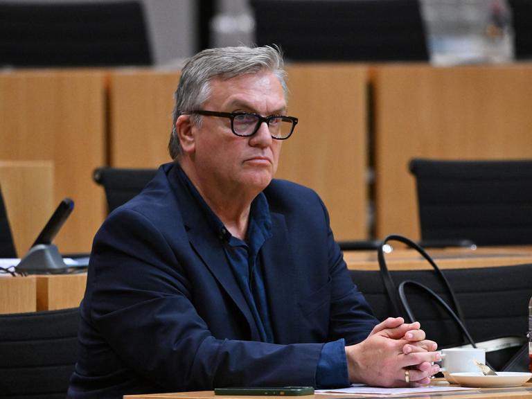 Hape Kerkeling sitzt während einer mündlichen Anhörung zu einem Parteiverbotsverfahren gegen die AfD auf Bundesebene im Plenarsaal des Thüringer Landtags. Er schaut ernst, seine Hände liegen auf dem Tisch, an dem er sitzt. Hape Kerkeling sitzt während einer mündlichen Anhörung zu einem Parteiverbotsverfahren gegen die AfD auf Bundesebene im Plenarsaal des Thüringer Landtags. Er schaut ernst, seine Hände liegen auf dem Tisch, an dem er sitzt.