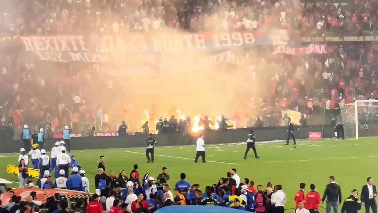 In einem Videoausschnitt sieht man Ordner auf dem Platz, die die Fans zurückhalten wollen, die schon bengalische Feuer geworfen haben.