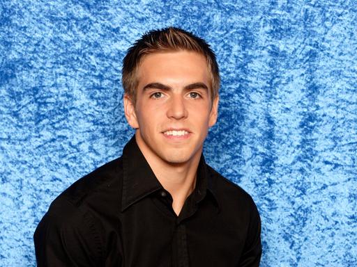Poträt des Fußballers Philipp Lahm im schwarzen Hemd vor blauem Hintergrund.