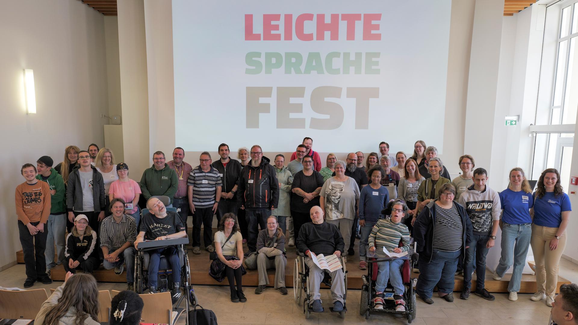 Auf einer Bühne sind viele Menschen zusammen. Einige sitzen im Roll-Stuhl. Auf einer Bühne sind viele Menschen zusammen. Einige sitzen im Roll-Stuhl.