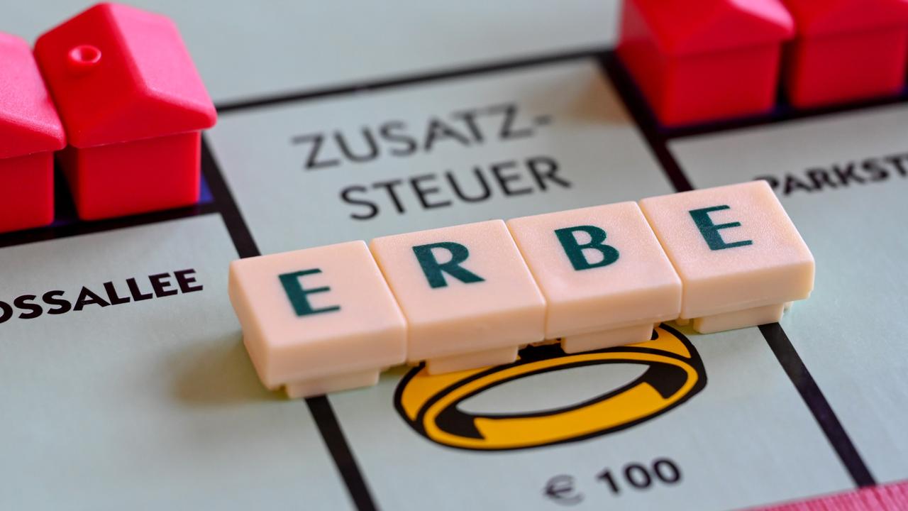 Ein Monopoly-Spielbrett mit dem aus Scrabble-Buchstaben gelegten Wort Erbe, das auf dem Feld "Zusatzsteuer" liegt