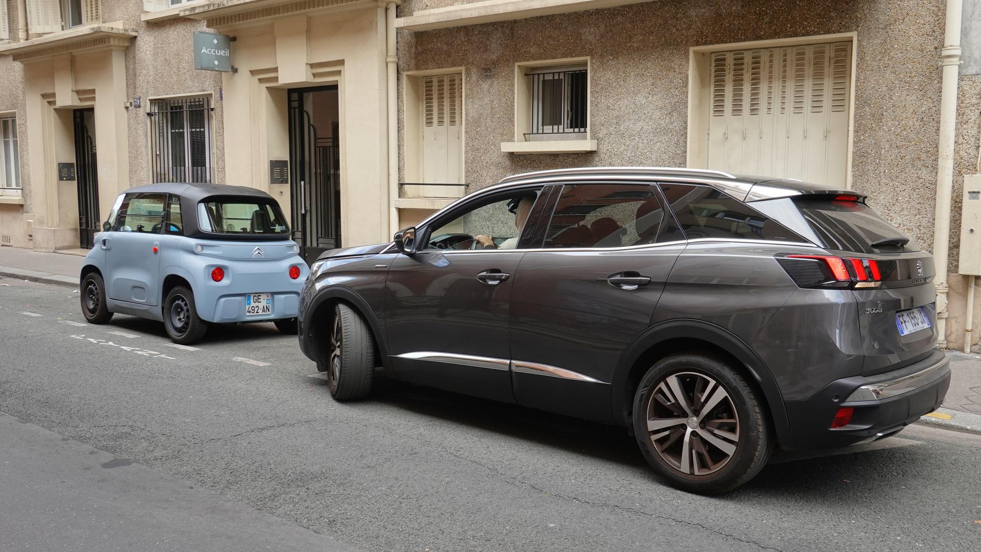 Ein kleines Auto und ein SUV parken hintereinander. Das Foto wurde in Paris aufgenommen. 