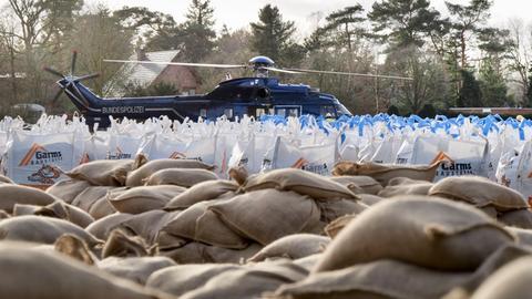 Sandsäcke liegen zum Abtransport bereit. Im Hintergrund ist ein Hubschrauber der Bundespolizei.