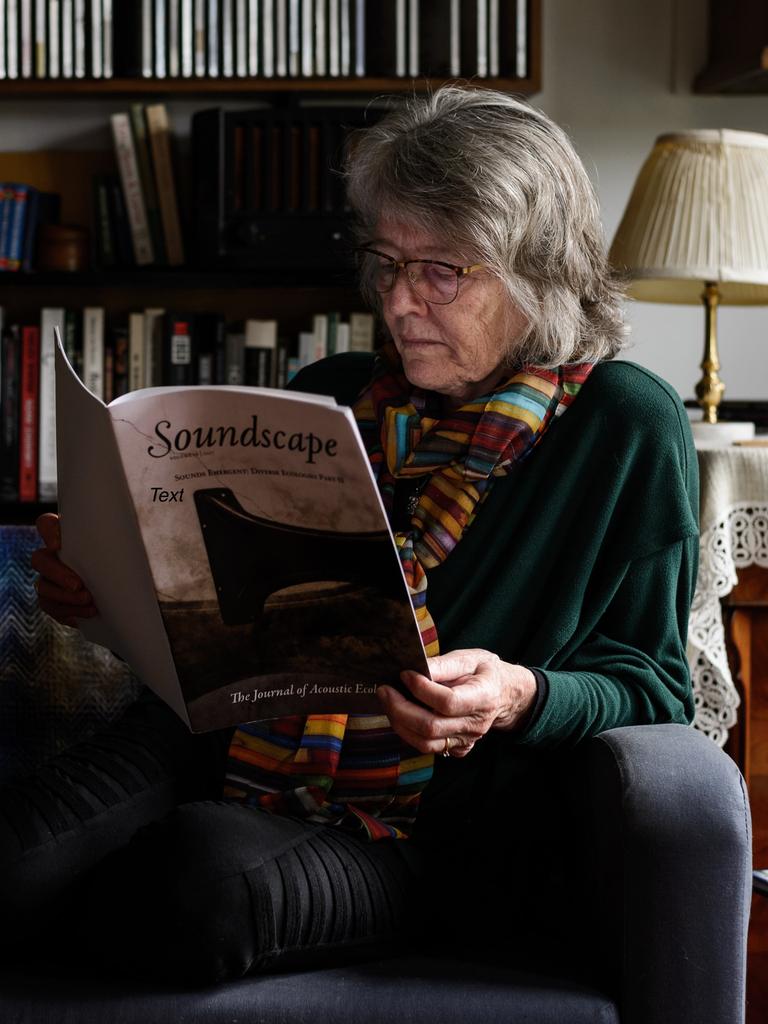 Eine Frau mit schulterlangen Haaren und Brille sitzt auf einem Sessel und liest in einer Partitur mit dem Titel "Soundscape"