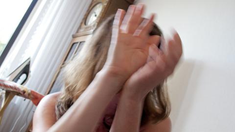 Symbolfoto zum Thema Häusliche Gewalt gegen Frauen: Eine Frau hält schützend ihre Hände vor das Gesicht