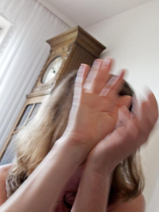 Symbolfoto zum Thema Häusliche Gewalt gegen Frauen: Eine Frau hält schützend ihre Hände vor das Gesicht