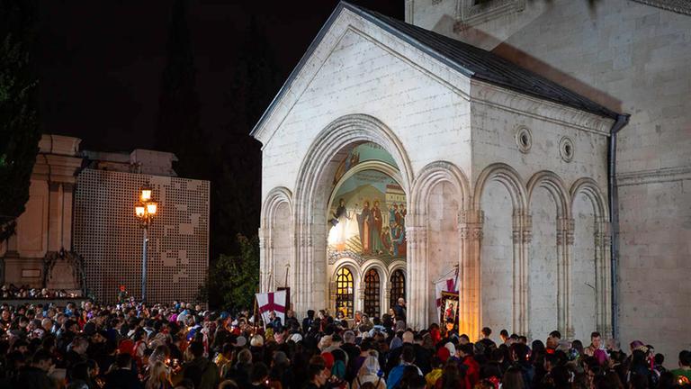 In Tiflis feiern Menschen das orthodoxe Osterfest und protestieren gegen das geplante Agentengesetz. Die Menschen halten zum Teil Flaggen in den Händen und haben sich an einer Kirche versammelt.