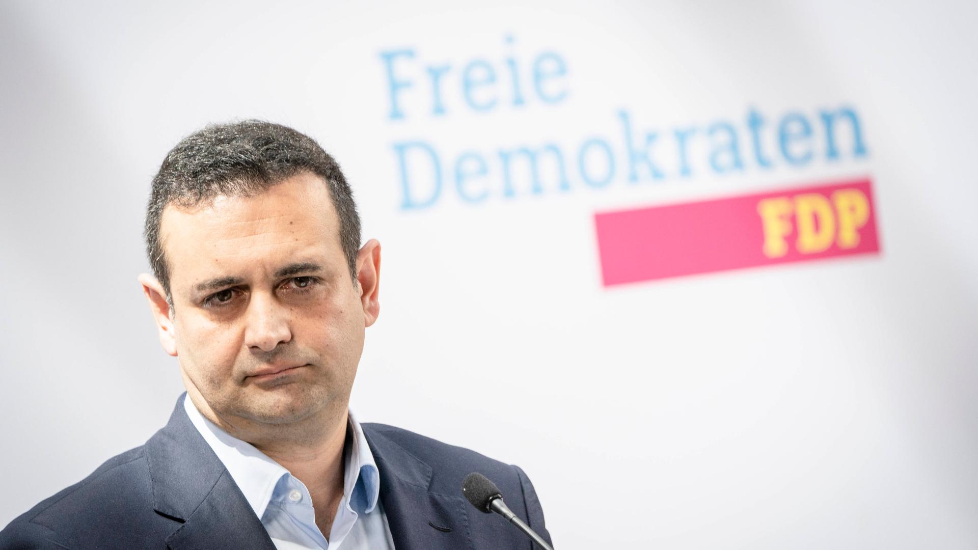 FDP-Generalsekretär Djir-Sarai sitzt auf einer Pressekonferenz vor einer Wand mit dem Logo der FDP.