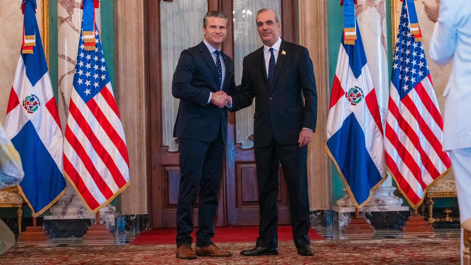 Der dominikanische Präsident Luis Abinader (rechts im Bild) schüttelt in Santo Domingo Hände mit US-Verteidigungsminister Pete Hegseth, neben den Politikern sind Flaggen beider Länder zu sehen. Der dominikanische Präsident Luis Abinader (rechts im Bild) schüttelt in Santo Domingo Hände mit US-Verteidigungsminister Pete Hegseth, neben den Politikern sind Flaggen beider Länder zu sehen.