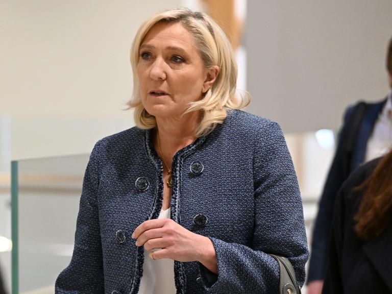 Die Rechtspopulistin Marine Le Pen im Pariser Gericht, wo das Urteil gegen sie verkündet wurde. Sie trägt eine blaue Jacke und schaut ernst. 